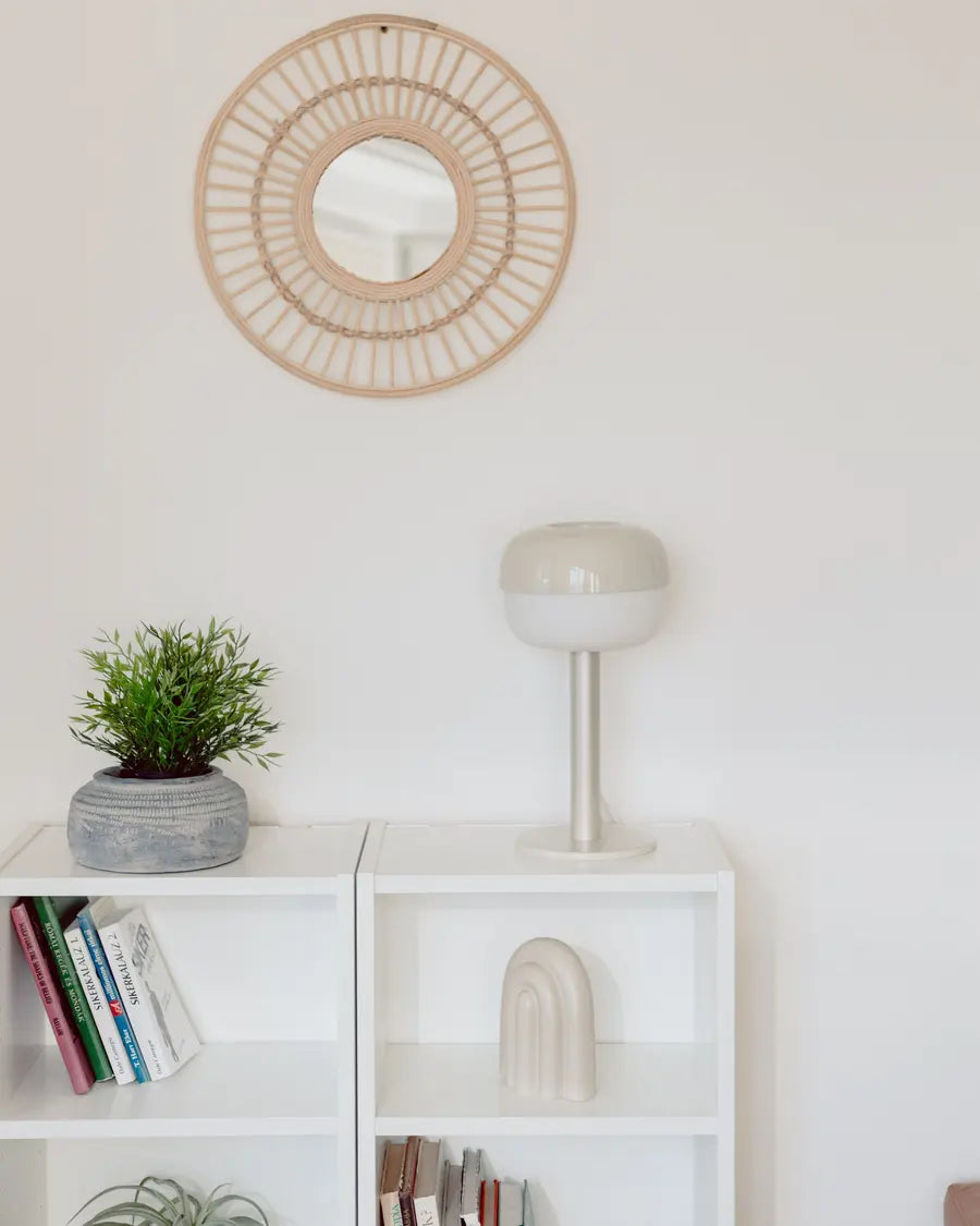 Miroir rond à cadre en fibres naturelles sur un mur clair