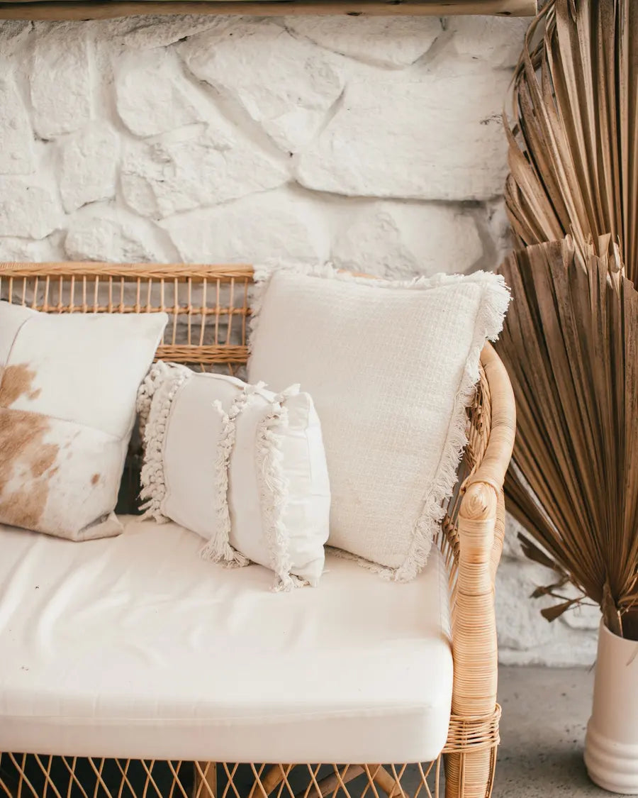 Coussins blancs à franges sur un fauteuil tressé